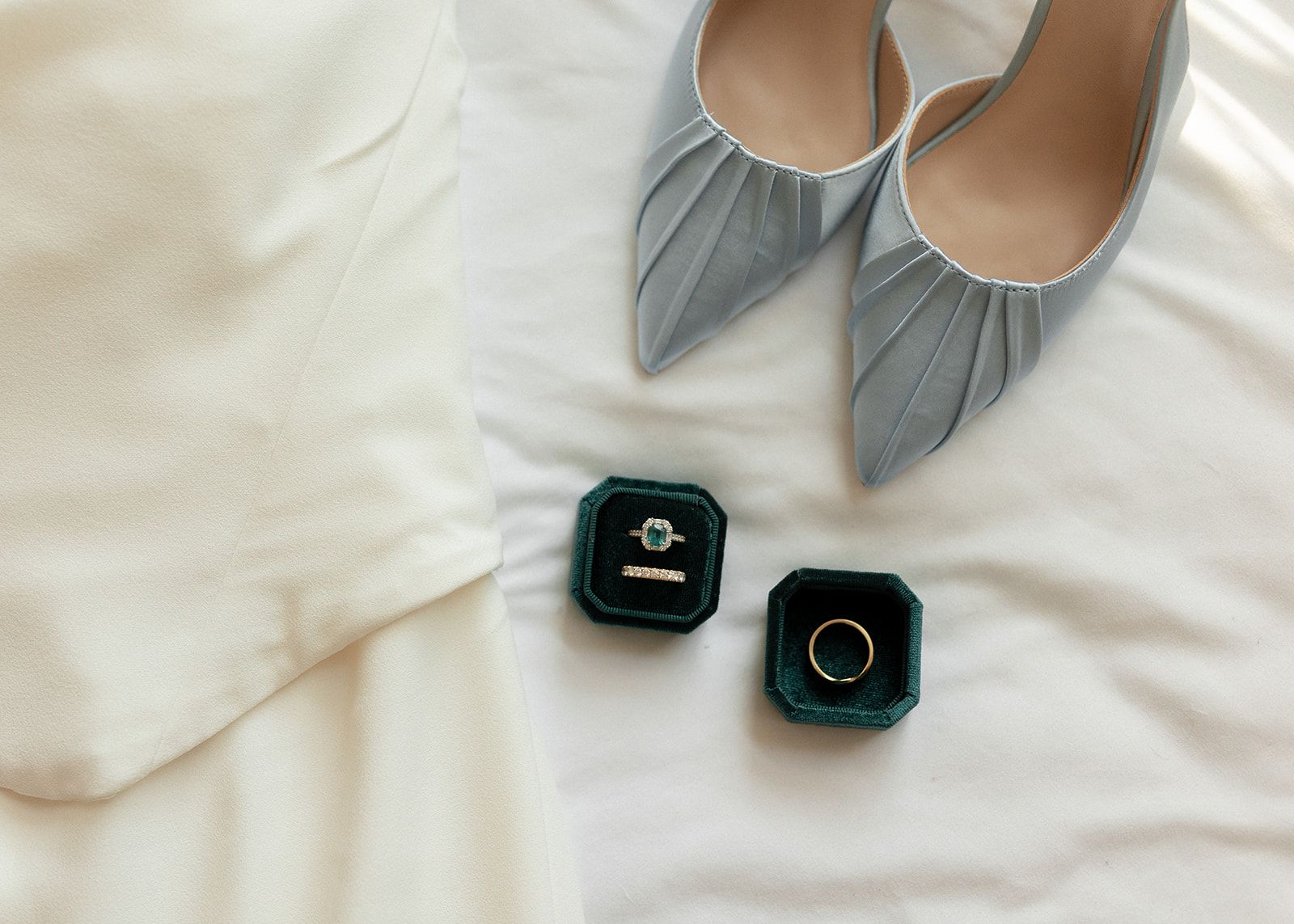 Collection of elegant ballet flats and ring boxes arranged on white fabric.