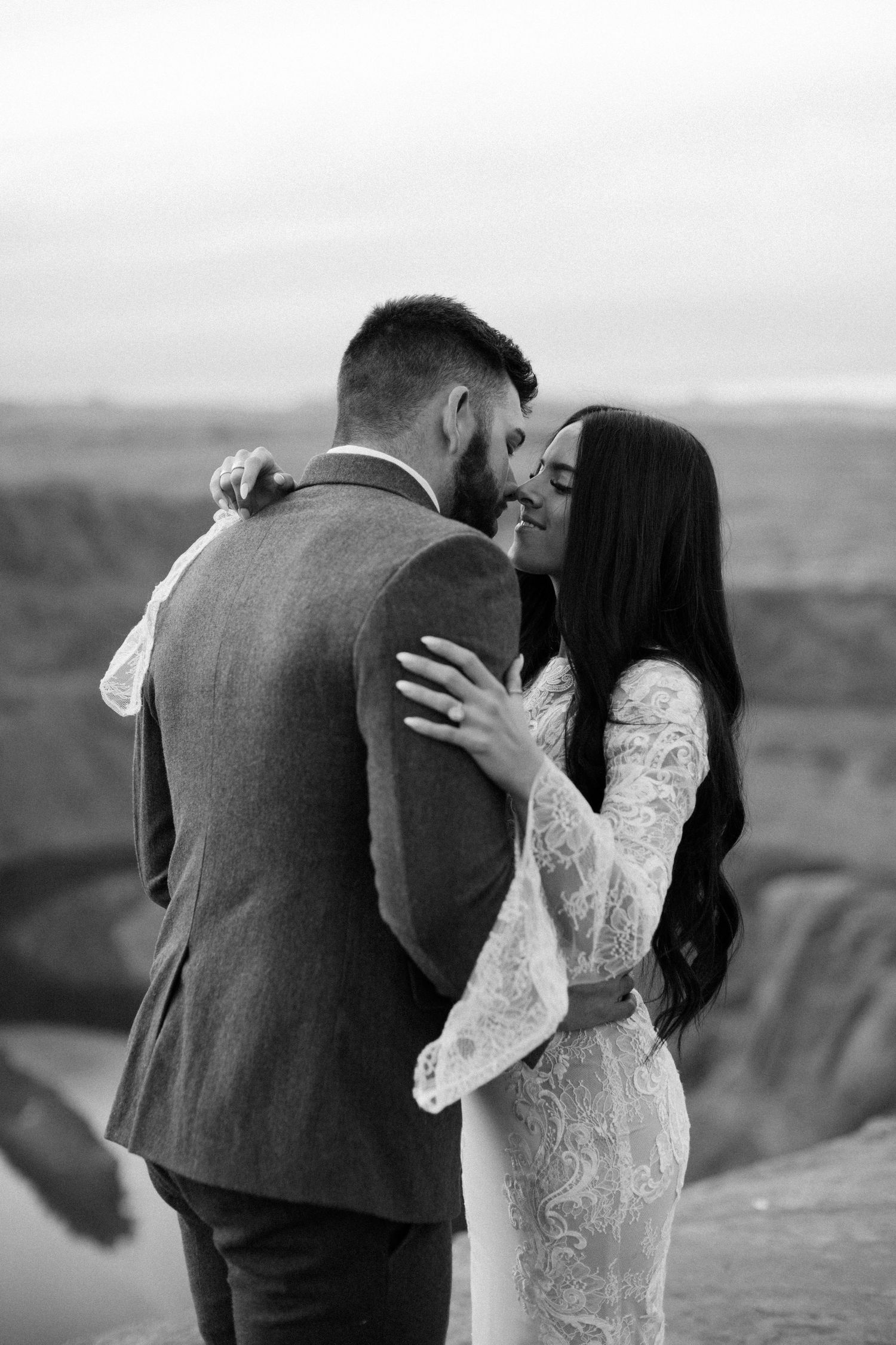 Black and white photo of bride and groom sharing an intimate moment at the edge of Horseshoe Bend canyon.
